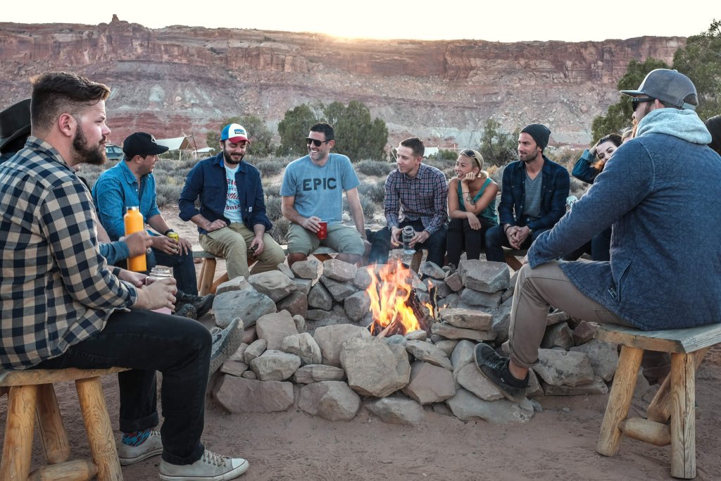 Group of young people sitting around a bonfire.